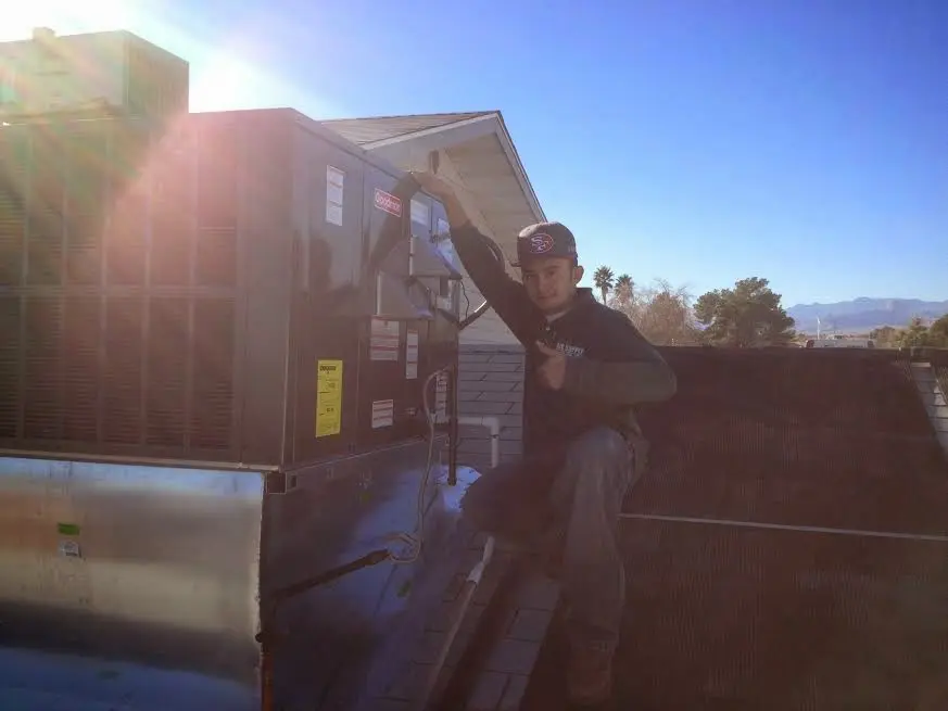 HVAC technician performing AC Tune-Up on a rooftop unit in Firebaugh