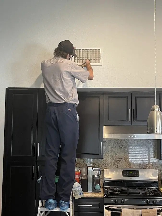 Technician inspecting an air vent during HVAC service in Firebaugh